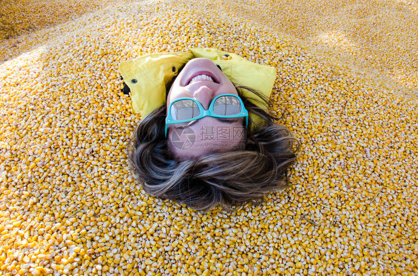 成年女全身被覆盖并埋在玉米坑的玉米内核中图片