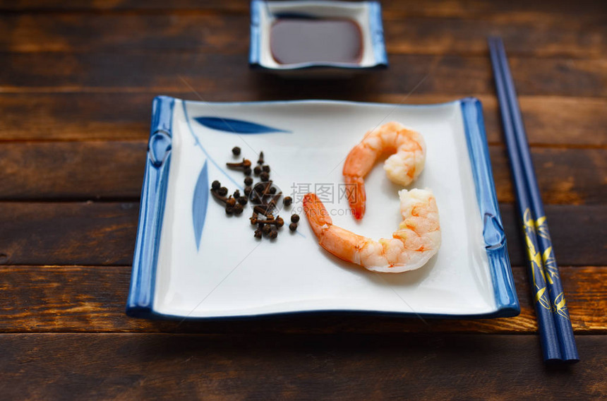 在日本传统盘子和筷子上加香料的鲜煮虾图片