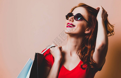 黄色背景上提着购物袋的红发女人背景图片