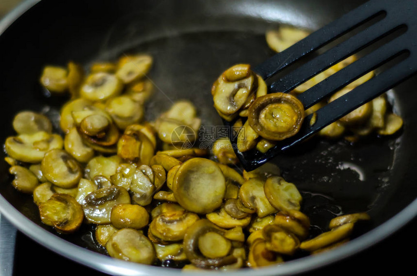 切片的蘑菇炒成黄油在锅里素食餐图片