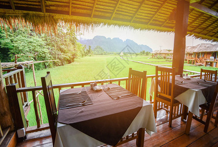 亚洲山背景下的餐厅自然绿景稻田景观中带餐桌的木制露台图片