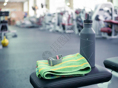 一个水瓶和运动手表在健身房长椅上的特写镜头图片