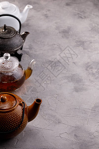 灰色带纹理的背景上连续摆放着各种样的茶壶喝茶的概念特写文图片
