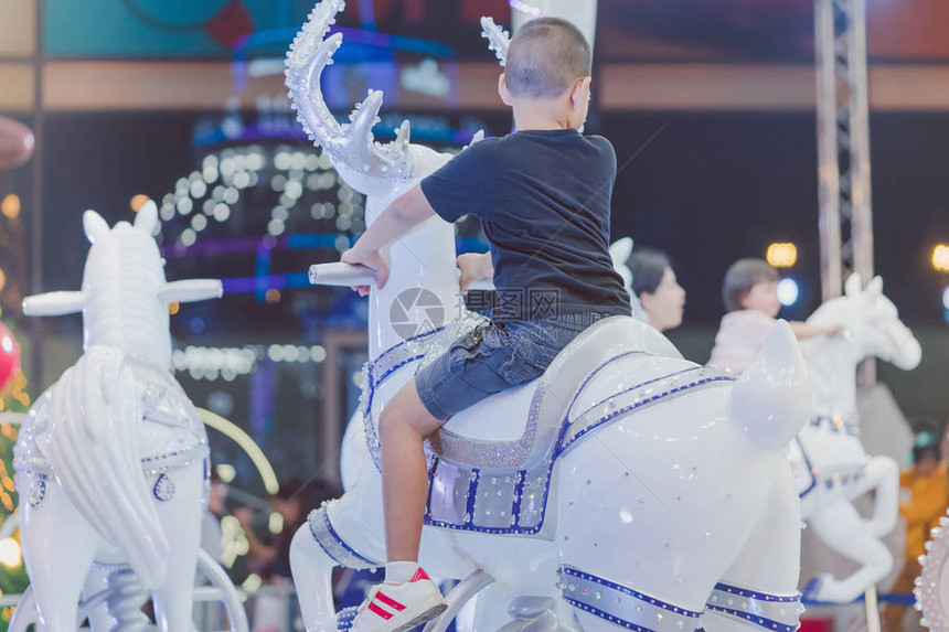 可爱的亚洲小男孩在圣诞游乐场骑着一匹快图片