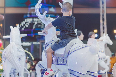 可爱的亚洲小男孩在圣诞游乐场骑着一匹快图片