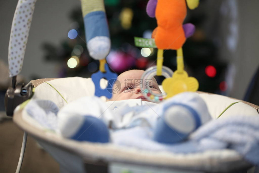 新生有趣的婴儿在摇篮里和圣诞树对图片