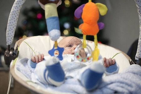 新生有趣的婴儿在摇篮里和圣诞树对图片