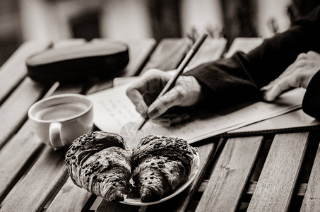 年轻女商人的手在早餐时间用纸上写一个平衡的平衡图片以图片