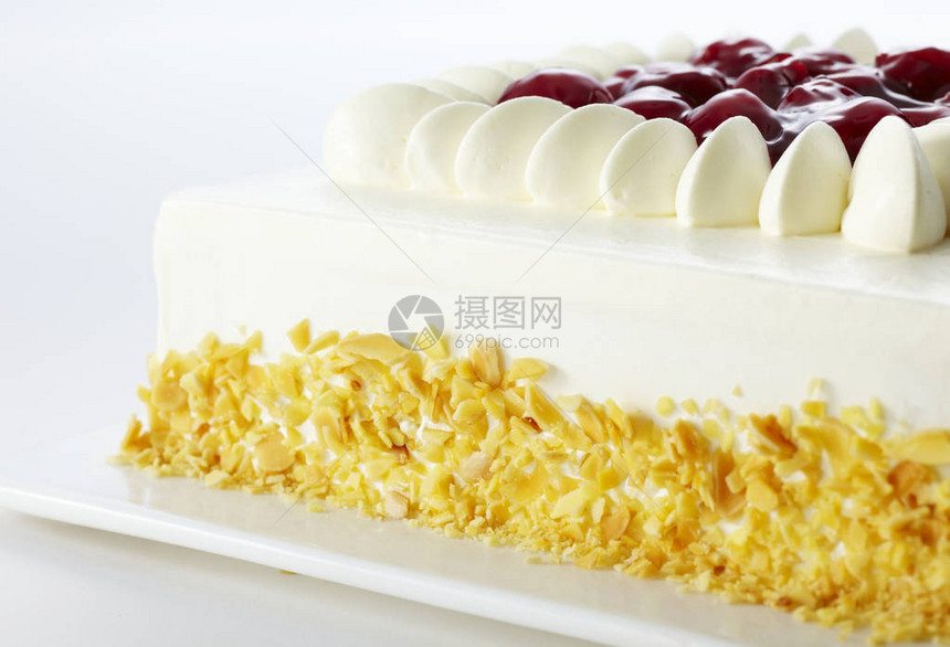 甜美味的蛋糕装饰着白奶油和樱桃在白图片