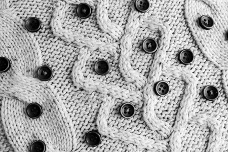 柔软暖和的天然毛衣的美丽纹理织有丝线黑白圆形小按钮背图片