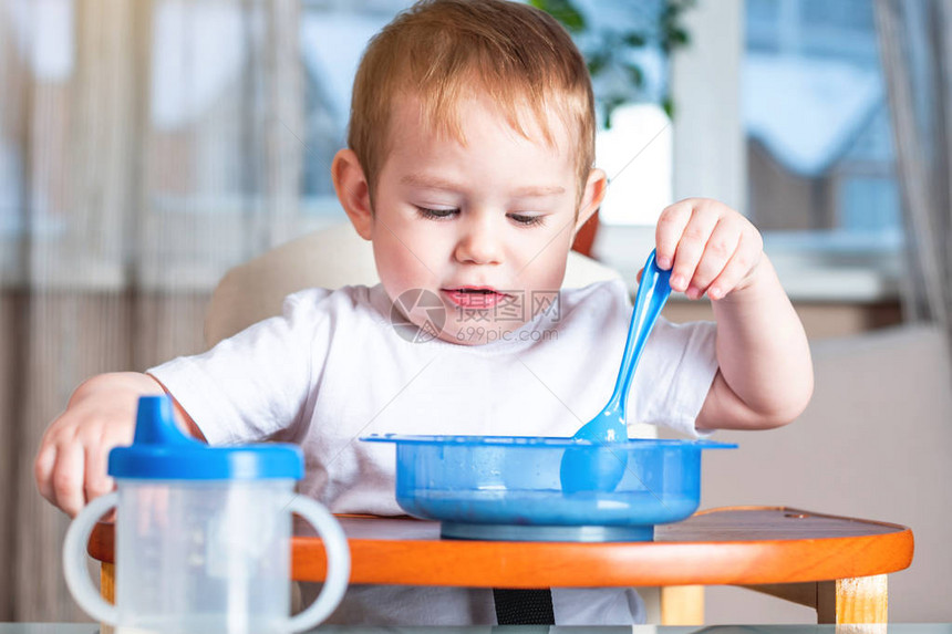 小男孩在厨房的儿童餐桌旁学习用勺子自己吃饭健康婴图片