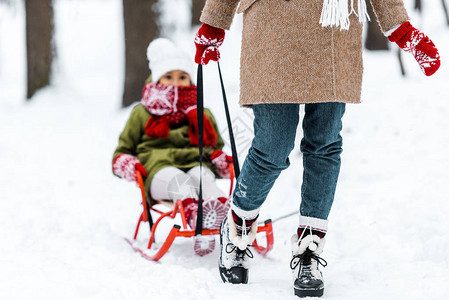 母亲用温暖衣服拉着女儿在冬季公图片