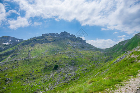 绵延在风景如画的群山之间的绿色草地背景图片