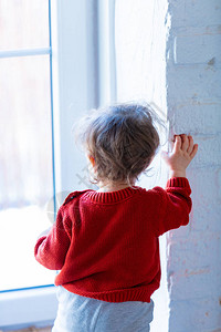 小孩待在墙边看着窗外的窗户图片