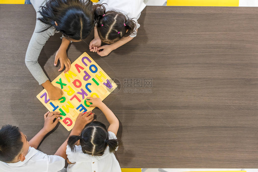 亚洲教师与亚洲学生一起玩彩色字母木块的平面片图片