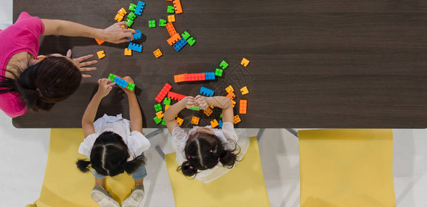 一群孩子和老师在教室里玩五颜六色的玩具图片