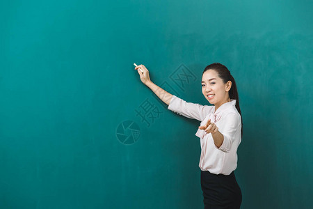 亚洲教师在绿板上的粉笔指向相机图片