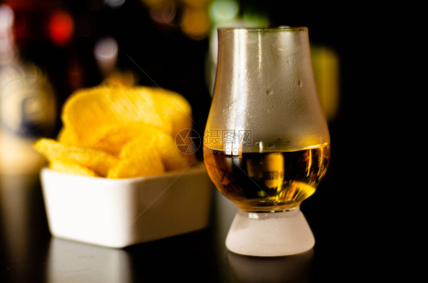 杯威士忌加冰块和咸点心在酒吧背景派图片