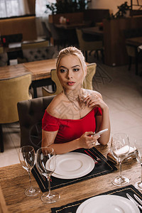 穿着红裙子的有吸引力的女友坐在餐厅等男朋友图片