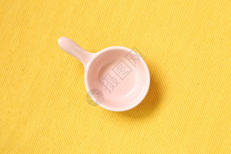 黄色织物背景上的粉红色陶瓷碗图片