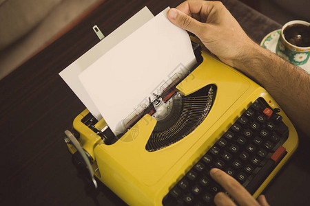 作家一边用旧的黄色打字机打字图片