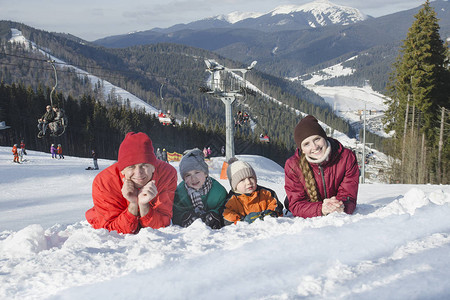 父亲母亲和两个儿子在滑雪度假胜地的背景中撒谎并微笑日图片