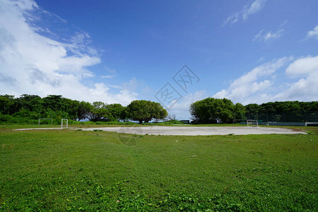 蓝天白云下绿草环绕的足球场远景图片