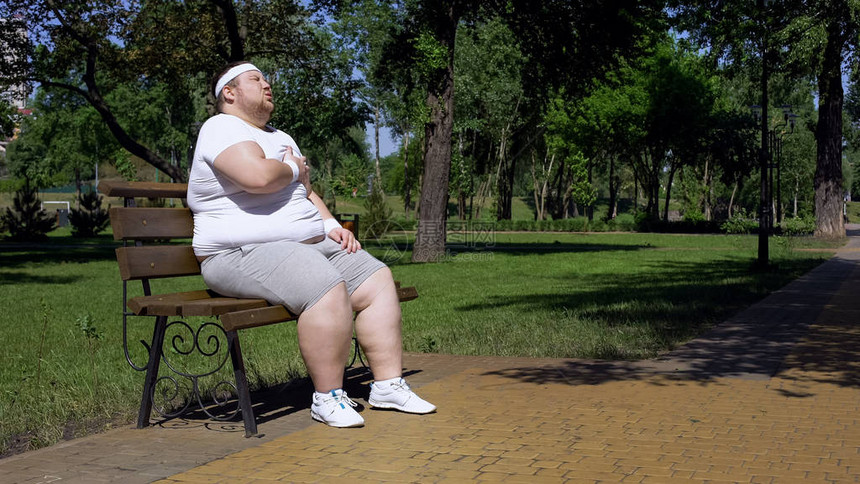 慢跑后精疲力尽的胖女孩在长凳上休息一分钟图片