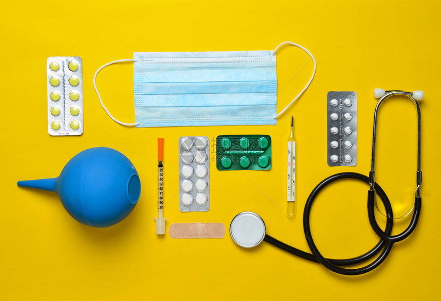 黄色背景上的医疗设备灌肠剂水泡丸笔记本听诊器注射器温度计医学概念图片
