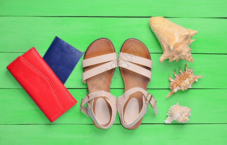 时尚女式凉鞋护照红色钱包绿色木地板上的贝壳出海旅游的图片