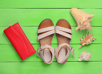 时尚女式凉鞋红色钱包绿色木地板上的贝壳出海旅游的图片