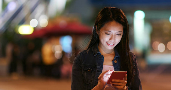 女人在城市街道上用手机发送短信图片
