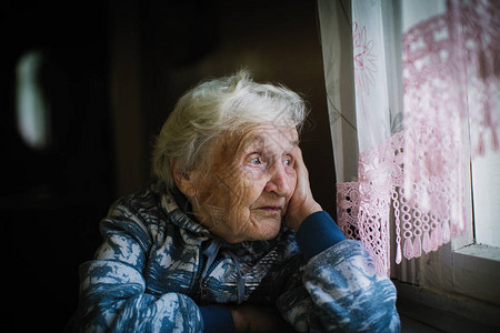 坐在桌子上看窗外的老妇人图片