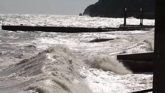 一个大浪在日落背景下的防波堤特写镜头上爆发海景海水风暴波击中石码头图片