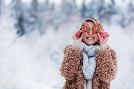 穿着大衣的漂亮女孩在雪林里吃饼干情人节圣图片