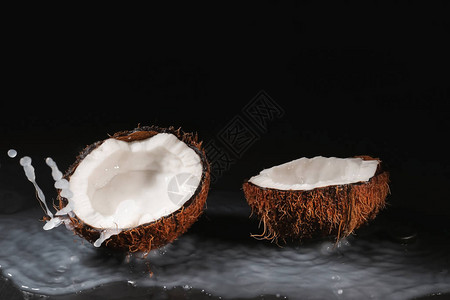 成熟的椰子和牛奶在深色背景上飞溅图片