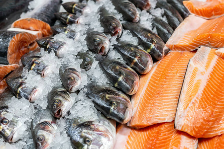 鱼市场上碎冰上的新鲜海商店陈列柜台上的生多拉鲈鱼和鲑图片