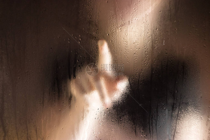 美丽的小女孩触摸湿润的窗户和手指在雨图片