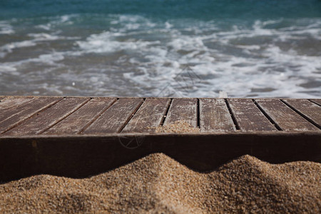 背景中的沙子和蓝色大海中的木板图片