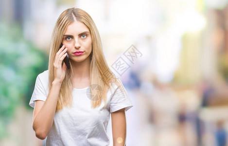 年轻漂亮的金发女郎在孤立的背景下用智能手机说话图片