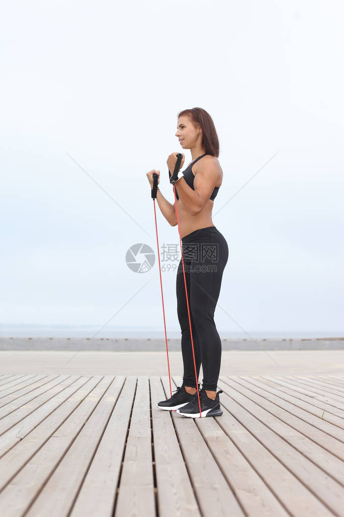 黑发女人用橡皮筋锻炼户外健身图片