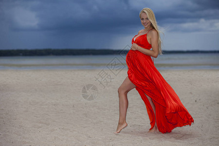 身着红亮裙子的年轻正面女孩在阴云多彩背景图片