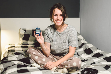 年轻的白种女人在家卧室的床上使用测量血糖的装置的技术图片