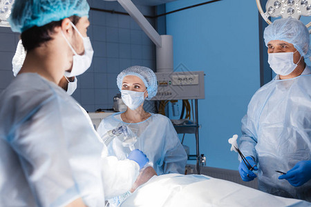 穿制服和戴面罩的无神论者在手术室一起工作图片