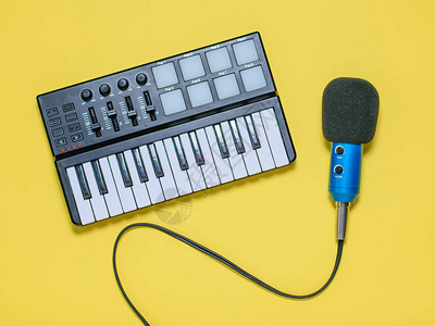 音乐混音器和蓝色麦克风与黄色背景上的电线用于录制音乐曲目的设备从顶部图片