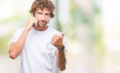英俊的西班牙裔男模特在孤立的背景下用智能手机说话背景图片
