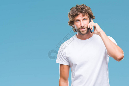 英俊的西班牙裔男模特在孤立的背景下用智能手机说话背景图片