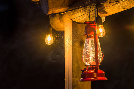 古老的红色金属和玻璃飓风雨挂在黄昏时分的铁原木小屋外图片