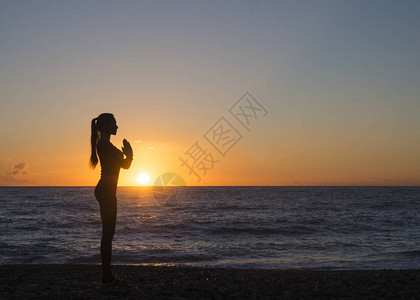 静思瑜伽中的年轻女似乎俯视着美丽的日落图片