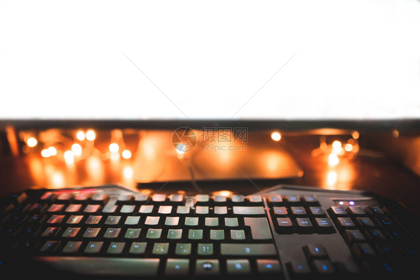 背景键盘鼠标和电脑显示器在晚上有温暖的灯光晚上在电脑前工作复制空图片
